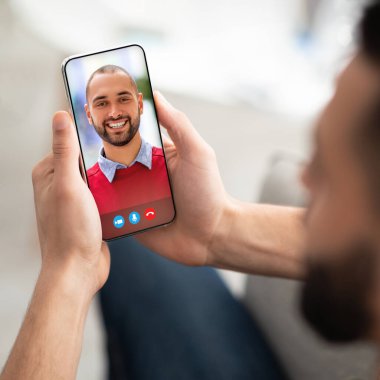 Genç adam Arap arkadaşıyla buluşmak için akıllı telefon kullanıyor.