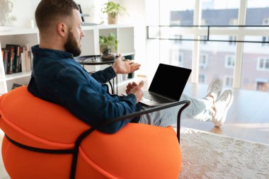 Boş ekranlı dizüstü bilgisayar kullanan adam içeride video çağrısı yapıyor