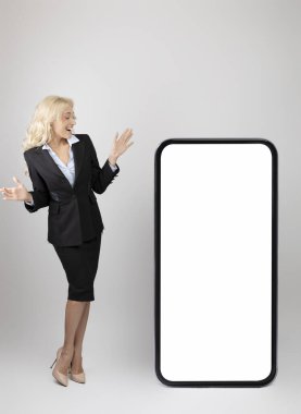 İş ilanı. Heyecanlı genç iş kadını beyaz ekranlı, boş akıllı telefona bakıyor.