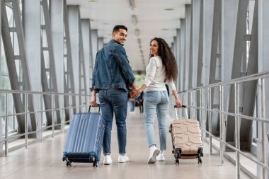 Romantik genç ortadoğu çifti havaalanı terminalinde birlikte yürüyor.