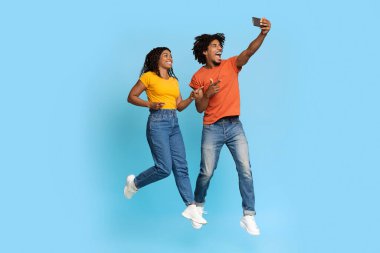 Neşeli Afro-Amerikalı aşıklar mavi ile selfie çekiyorlar.