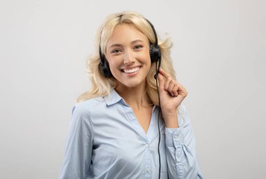 Müşteri hizmetleri operatörü. Mutlu kadın çağrı merkezi temsilcisinin portresi gri arka planda poz veriyor.