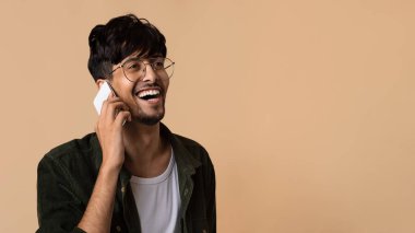 Mutlu Ortadoğulu adam bej rengi telefon görüşmesi yapıyor.