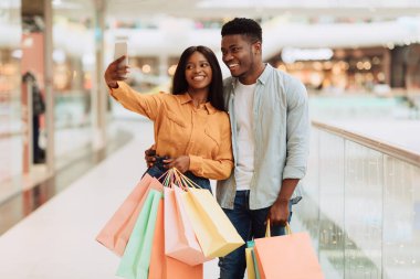Alışveriş merkezinde selfie çeken mutlu siyah çift.