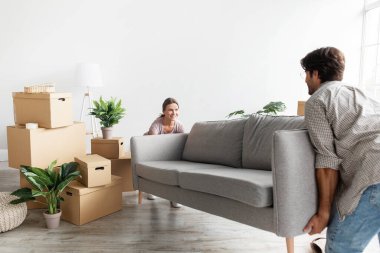 Gülümseyen bin yıllık Kafkasyalı çift gündelik koltuklarıyla odada karton kutular taşıyorlar, içlerini planlıyorlar.