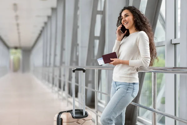 Красивая юная брюнетка разговаривает по мобильному телефону в ожидании в терминале аэропорта, — стоковое фото