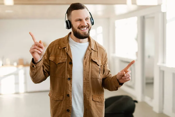 Glada skäggig kille lyssnar på favoritmusik bär hörlurar inomhus — Stockfoto