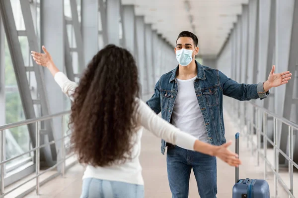 Feliz árabe chico usando médico máscara reunión novia en aeropuerto después de llegar —  Fotos de Stock