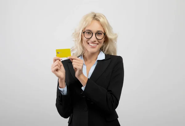 Gerente de banco feliz en ropa formal mostrando tarjeta de crédito y sonriendo a la cámara, recomendando servicios financieros — Foto de Stock