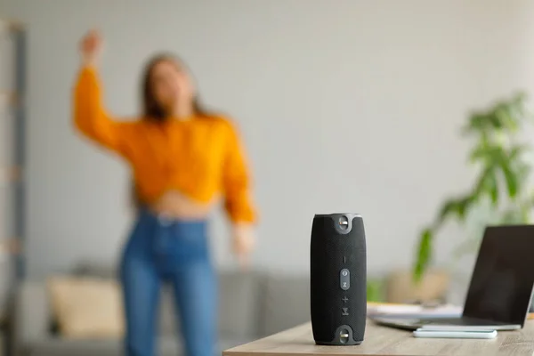 Jovencita bailando música popular en casa, enfoque selectivo en altavoz inalámbrico portátil, espacio para copiar —  Fotos de Stock