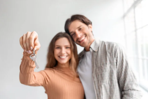 Satisfecho feliz joven pareja caucásica celebrar la compra de su propio apartamento en préstamo, mostrar las llaves en la habitación vacía —  Fotos de Stock