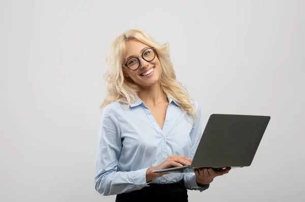 Retrato de excitada jovem empresária segurando laptop, trabalhando no computador e sorrindo para a câmera — Fotografia de Stock