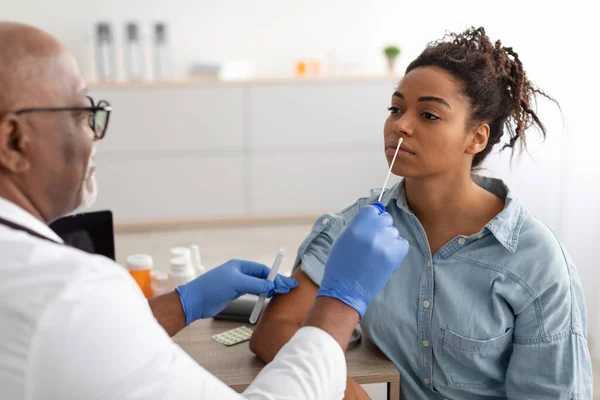 Médico tomando la muestra de prueba de PCR de una mujer negra potencialmente infectada —  Fotos de Stock