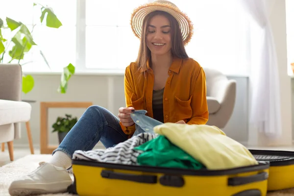 Підготовка до поїздок. Весела молода кавказька жінка упаковує валізу, готується до відпустки вдома, копіює місце. — стокове фото