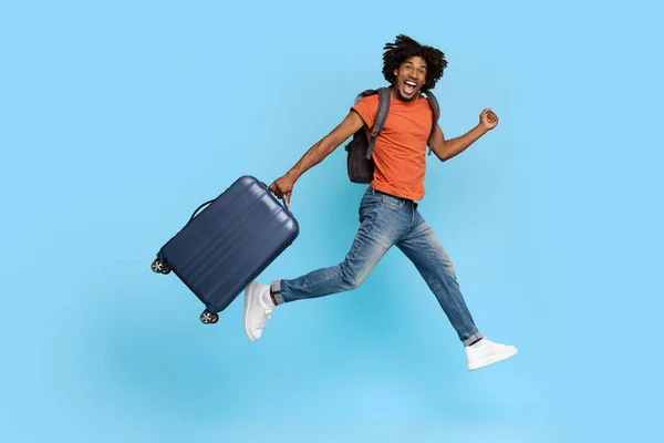 Gelukkig toeristisch jong zwart man met rugzak en bagage — Stockfoto