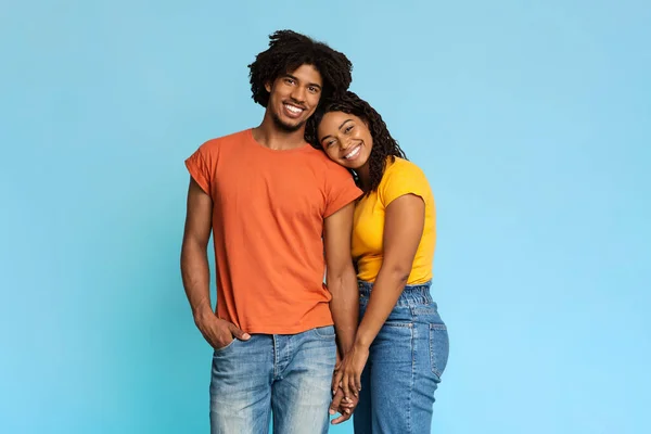 Feliz pareja afroamericana posando sobre azul, tomados de la mano — Foto de Stock