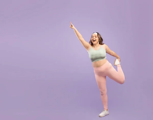 Glad förvånad glada plus storlek europeiska unga dam i sportkläder gör ben motion — Stockfoto