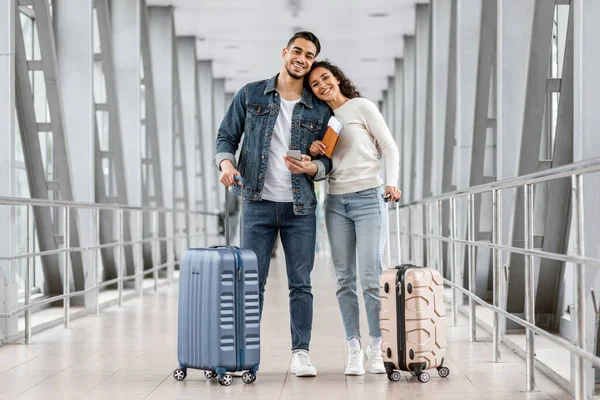 Alegre jovem Oriente Médio casal de pé no aeroporto com bagagem e Smartphone — Fotografia de Stock