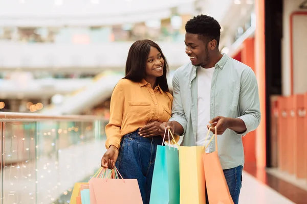 Feliz pareja negra sosteniendo bolsas de compras mirándose —  Fotos de Stock