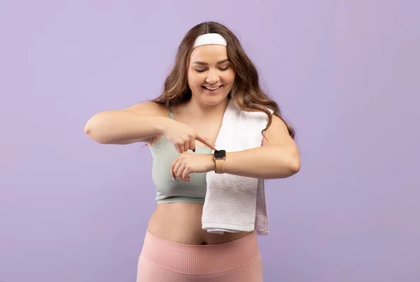 Felice felice eccitato plus size signora millenaria europea in abbigliamento sportivo con controllo del polso asciugamano sul fitness tracker — Foto Stock