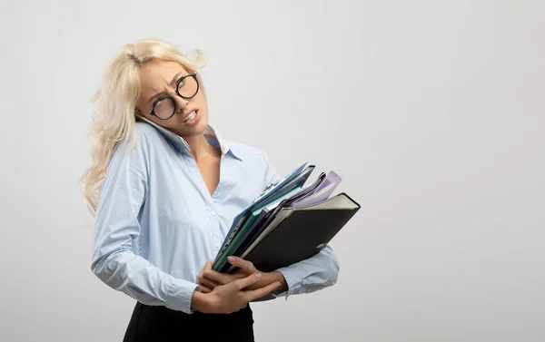 Stres žena kancelářská pracovnice s hromadou papírů mluvit na smartphone na pozadí světelného studia, volné místo — Stock fotografie