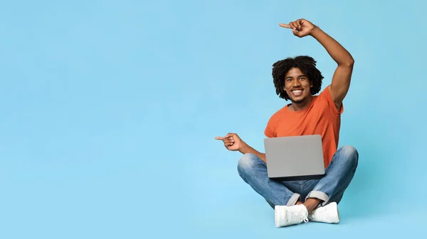 Przystojny czarny człowiek przy użyciu nowoczesnego laptopa, wskazując na przestrzeń kopiowania — Zdjęcie stockowe