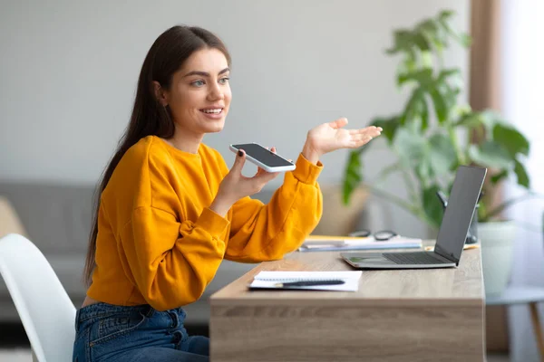 Glada unga kvinna som använder bärbar dator för distansarbete, gör online-samtal på smartphone hemifrån, kopiera utrymme — Stockfoto