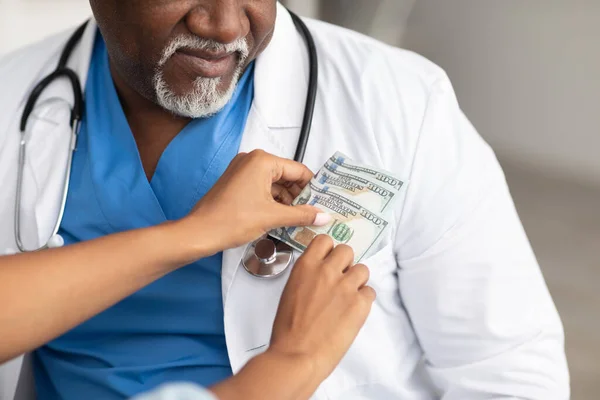 Mão feminina preta colocando dinheiro no bolso médicos, close-up — Fotografia de Stock