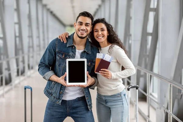 Mockup For Ad. Happy Arab Spouses Holding Blank Digital Tablet At Airport