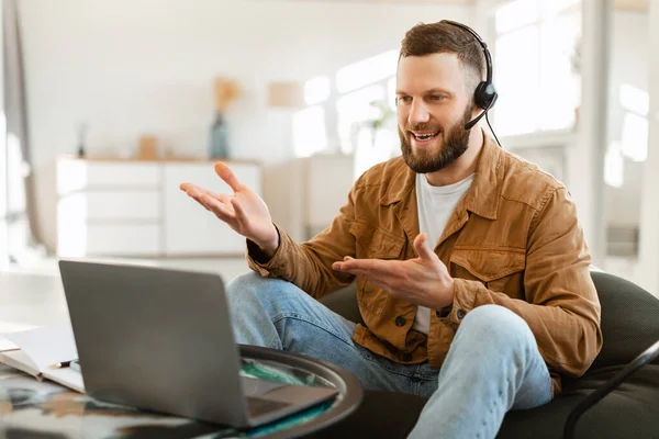 Evde kulaklık takan ve bilgisayar kullanan bir adam.