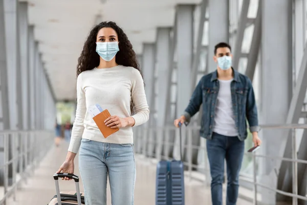 Nueva Normal. Hombre joven y mujer con máscaras médicas caminando en el aeropuerto —  Fotos de Stock