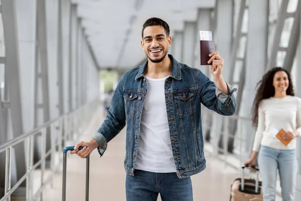 Hombre árabe viajero con maleta posando con pasaporte y entradas en el aeropuerto — Foto de Stock