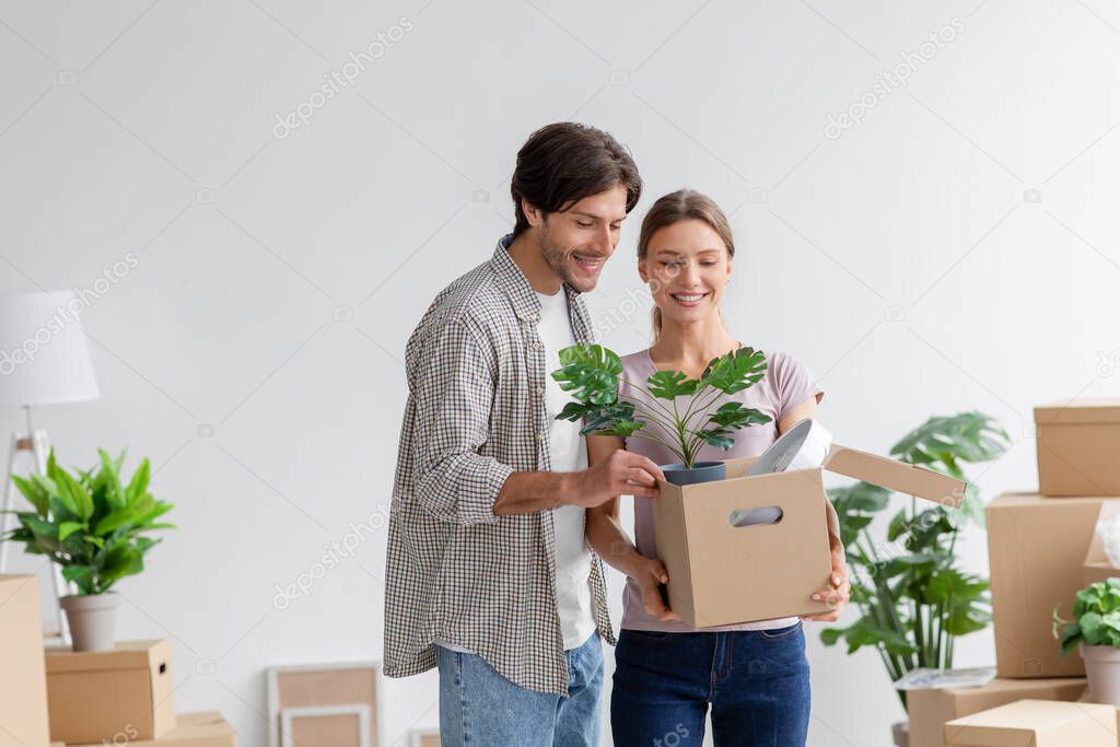 Cheerful millennial european male and female in casual enjoy packing belongings at cardboard box