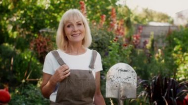 Elinde kürekle bahçede poz veren gülümseyen son sınıf güzeli.