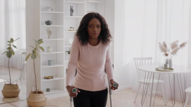 Afrikansk amerikansk ung kvinna står med kryckor hemma — Stockvideo