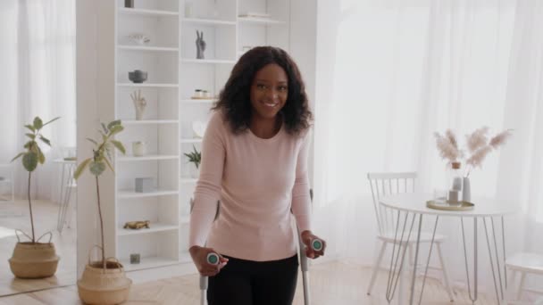 Signora africana con disabilità in piedi con stampelle sorridenti a casa — Video Stock