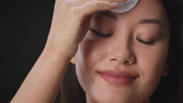 Hautreinigungskonzept. Junge schöne koreanische Frau Reinigung Gesicht mit Lotion und Baumwollkissen, Zeitlupe, freier Raum — Stockvideo