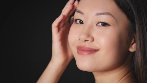 Schoonheidsverzorging concept. jong gelukkig mooi aziatisch vrouw aanraken van haar glad gezicht huid en glimlachen naar camera, lege ruimte — Stockvideo