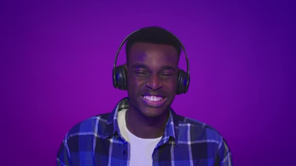 Mor Arkaplan Üzerine Kulaklık takan Mutlu Siyah Adam Müzik Dinliyor — Stok video