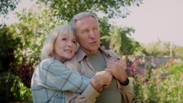 Romantisches Seniorenpaar entspannt sich im Garten, umarmt und redet — Stockvideo
