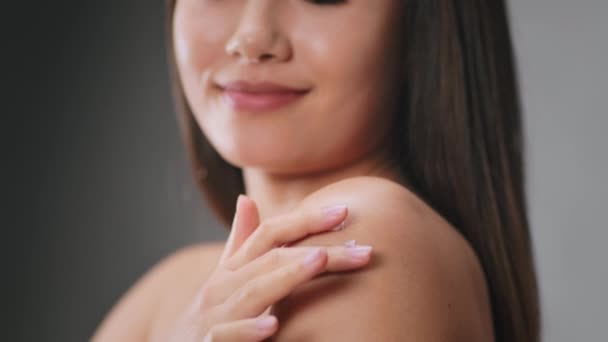 Sekret miękkiej skóry. Zbliżenie nierozpoznawalnej azjatki stosującej krem nawilżający na ramię, dbającej o ciało — Wideo stockowe