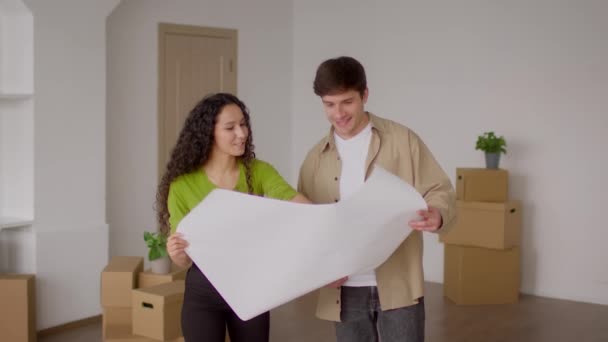 Pár držení papíru plán stojící mezi stěhování boxy doma — Stock video