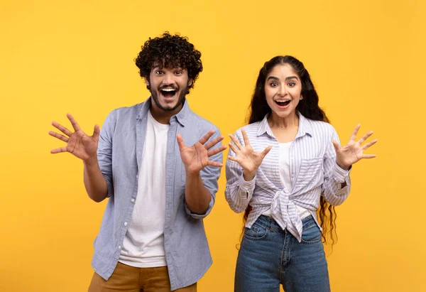 Συναισθηματική ινδική ζευγάρι gesturing μαζί, έχοντας έκπληξη εκφράσεις του προσώπου και δείχνει έκπληξη, κίτρινο φόντο — Φωτογραφία Αρχείου