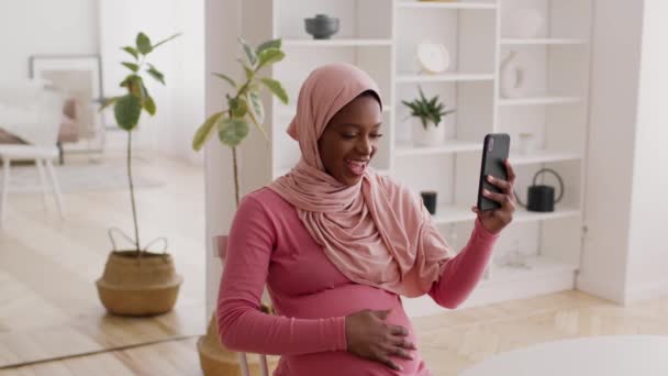 Grávida senhora africana no Hijab vídeo chamando via telefone interior — Vídeo de Stock