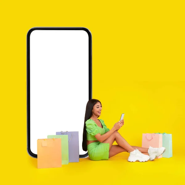Beyaz, boş, akıllı telefon ekranı ve alışveriş torbalarının yanında oturan kadın. — Stok fotoğraf