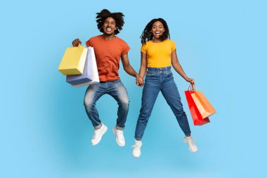 Alışveriş torbalarıyla zıplayan mutlu Afrikalı Amerikalı aşıklar