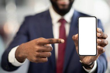Tanımlanamayan siyah iş adamı boş ekranla akıllı telefonu işaret ediyor.