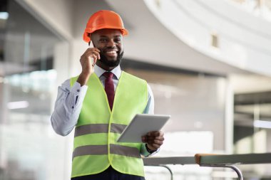 Mutlu Afrikalı Amerikalı mimar dijital tablet kullanarak telefon görüşmesi yapıyor.