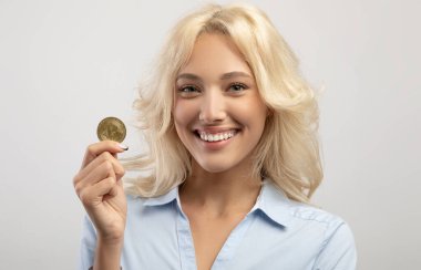 Kripto para madenciliği. Altın Bitcoin taşıyan heyecanlı iş kadınının portresi, çevrimiçi ticaretten zevk alıyor, yakın plan