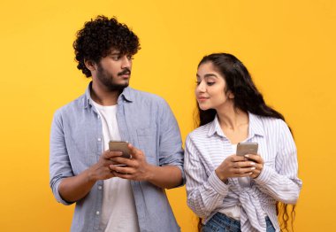 Şok olmuş Hintli kadın erkek arkadaşını gözetliyor, akıllı telefon kullanıyor, mesajlaşıyor ya da sosyal medyada haber yayını yapıyor.